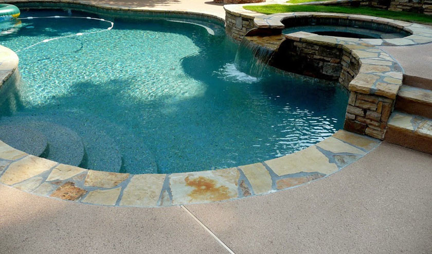 Bild på en amerikansk pool på baksidan av huset, med marksten i betong