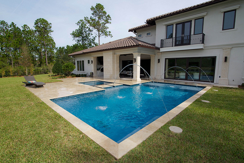 Пример оригинального дизайна: прямоугольный бассейн на заднем дворе в стиле модернизм с джакузи и покрытием из каменной брусчатки