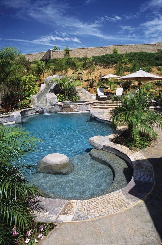 Example of an island style backyard stone and custom-shaped pool design in Phoenix