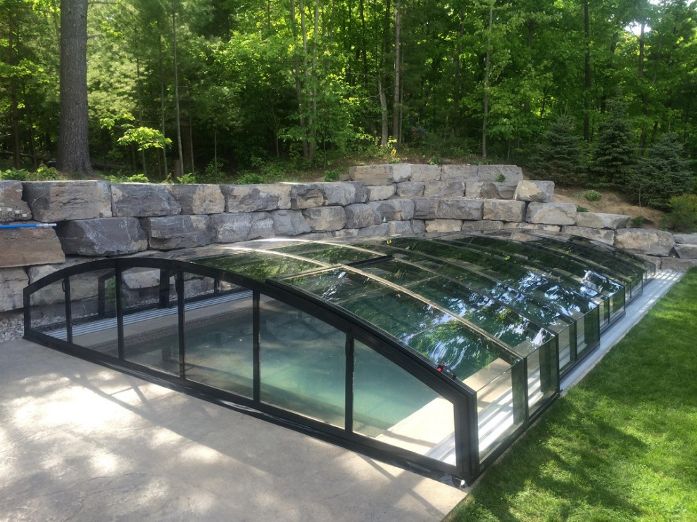 Foto di una piscina a sfioro infinito rettangolare di medie dimensioni e dietro casa con una dépendance a bordo piscina e cemento stampato