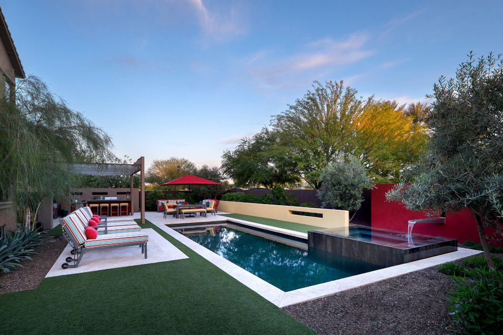 Modelo de piscina con fuente actual de tamaño medio rectangular en patio trasero con suelo de baldosas