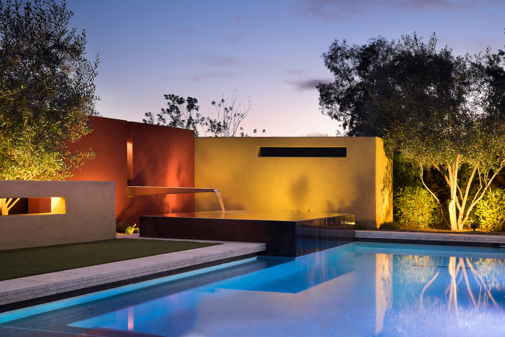 Ejemplo de piscina con fuente contemporánea de tamaño medio rectangular en patio trasero con suelo de baldosas