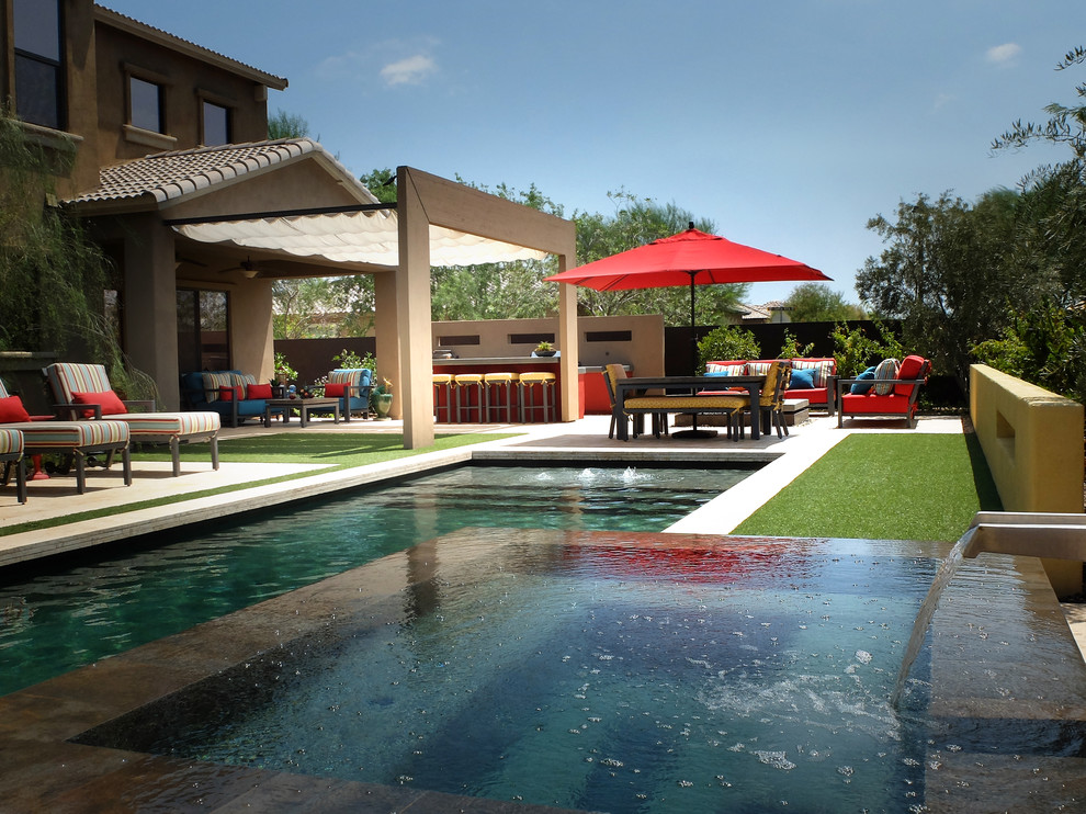 Immagine di una piscina design rettangolare di medie dimensioni e dietro casa con fontane e piastrelle