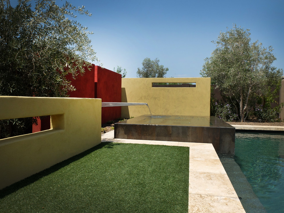 Modelo de piscina con fuente contemporánea de tamaño medio rectangular en patio trasero con suelo de baldosas