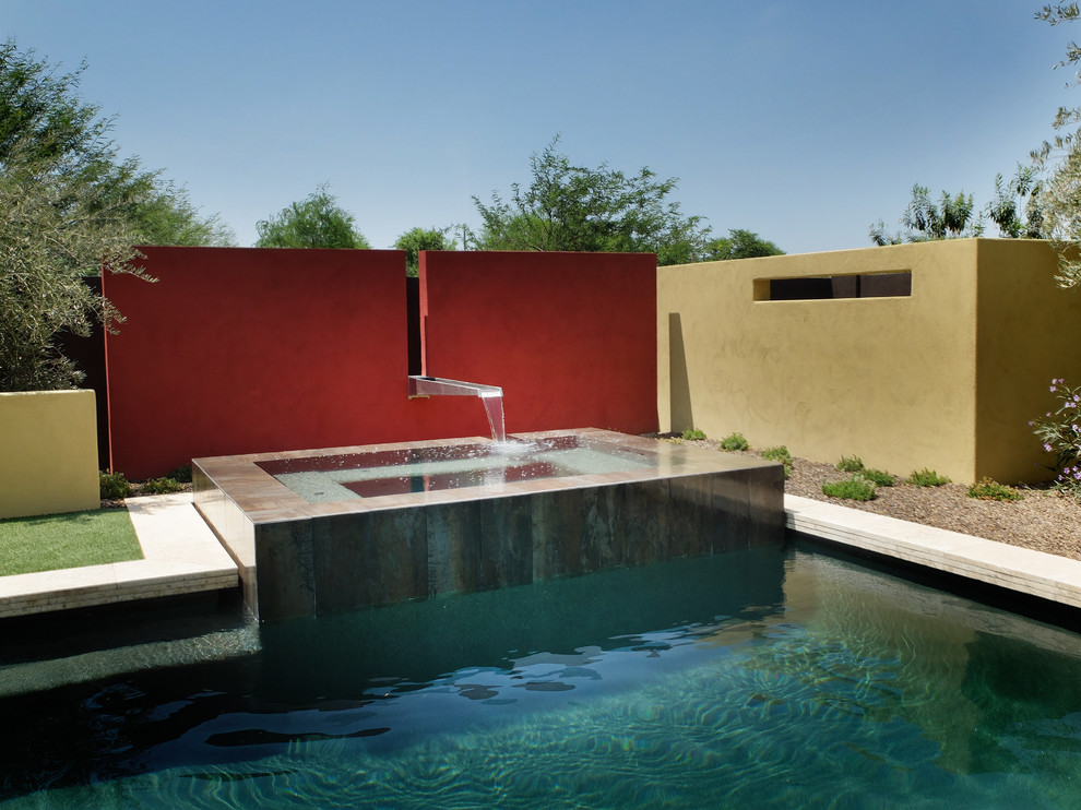 Diseño de piscina con fuente contemporánea de tamaño medio rectangular en patio trasero con suelo de baldosas