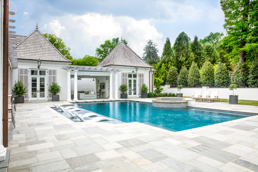 Exempel på en stor klassisk rektangulär pool på baksidan av huset, med naturstensplattor och poolhus
