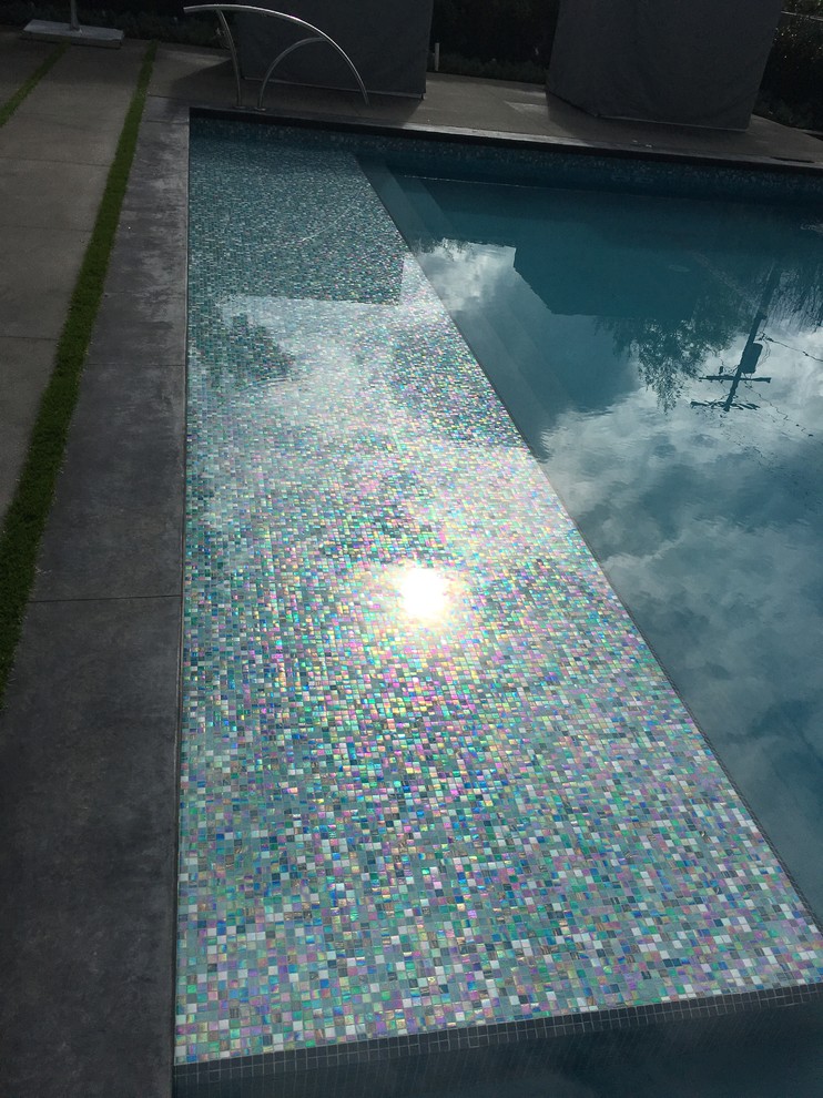 Imagen de piscina infinita minimalista grande rectangular en patio trasero con suelo de baldosas