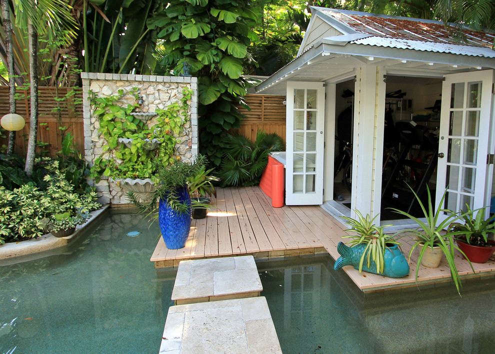 Imagen de casa de la piscina y piscina tropical grande a medida en patio trasero con adoquines de piedra natural