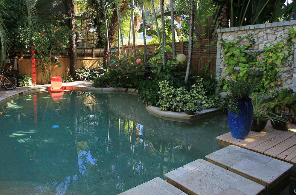 Exempel på en stor exotisk anpassad pool på baksidan av huset, med en fontän och naturstensplattor