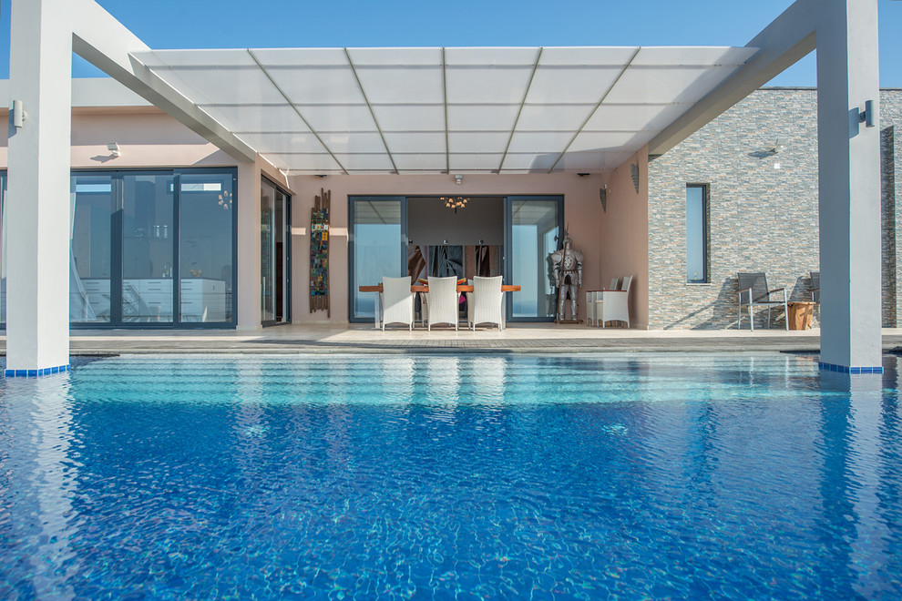 This is an example of a large modern back custom shaped lengths swimming pool in Copenhagen with tiled flooring.