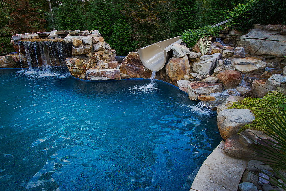 Imagen de piscina con fuente natural ecléctica grande a medida en patio trasero con adoquines de piedra natural