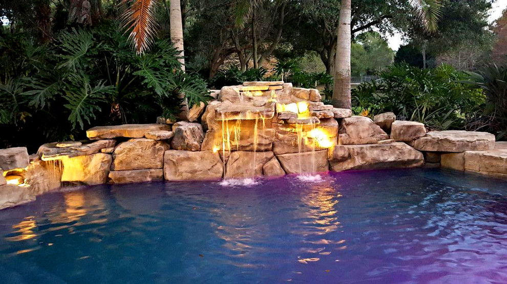 This is an example of a rustic back above ground swimming pool in Orlando with a water feature.