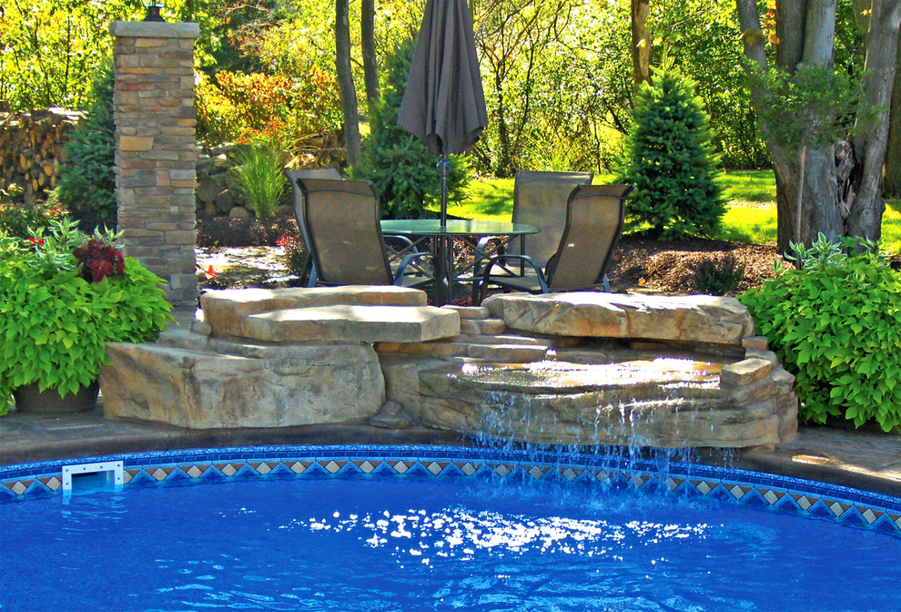 This is an example of a rustic back swimming pool in Cincinnati with a water feature.