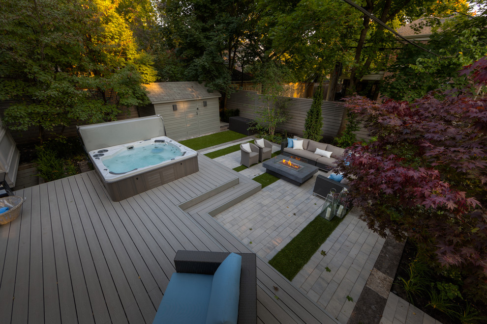 На фото: большой наземный, прямоугольный бассейн на заднем дворе в современном стиле с джакузи и настилом с