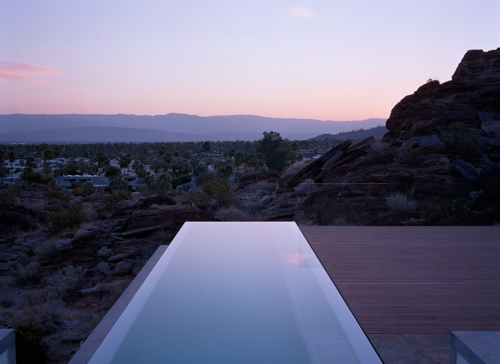 Esempio di una piscina a sfioro infinito moderna rettangolare di medie dimensioni e dietro casa con pedane
