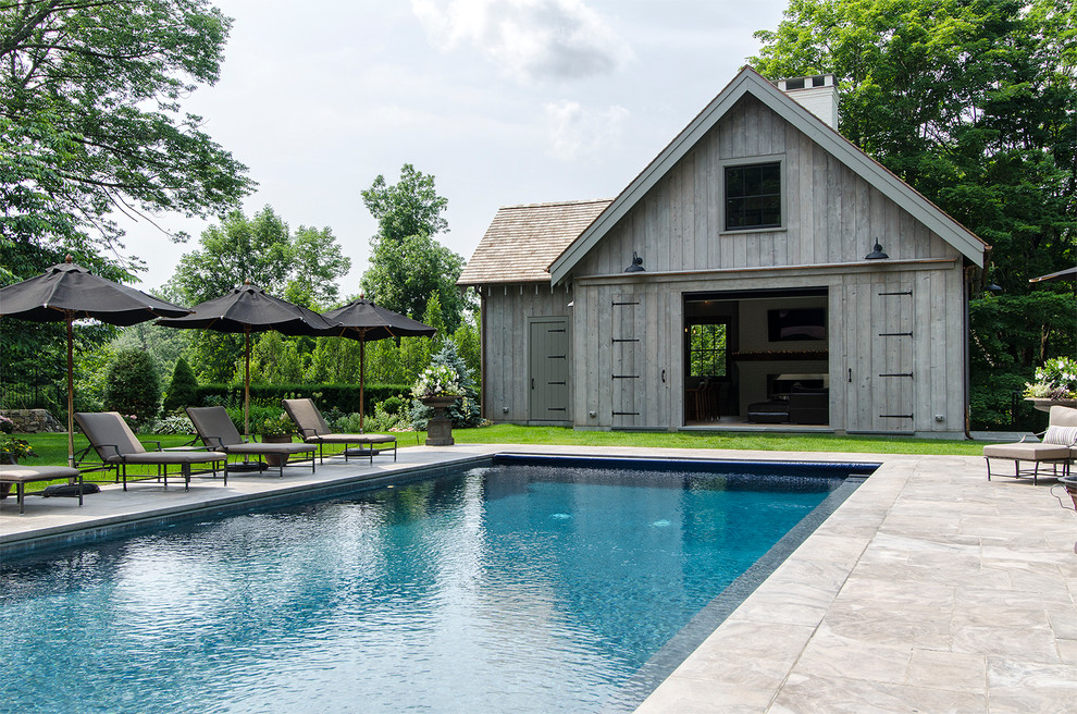 Immagine di una grande piscina monocorsia country rettangolare dietro casa con una dépendance a bordo piscina e pavimentazioni in pietra naturale