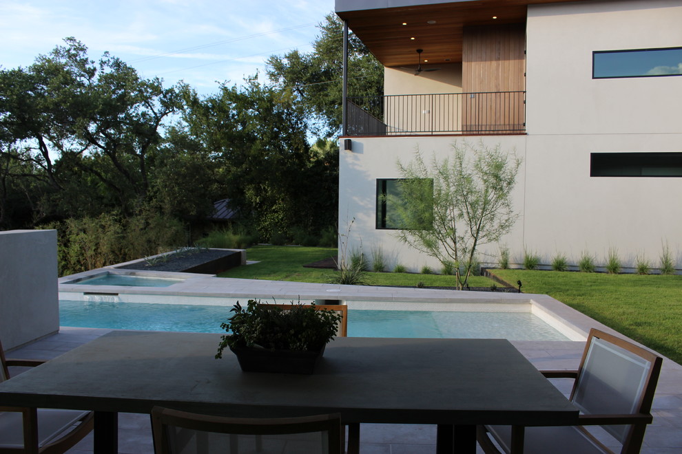 Idee per una piscina a sfioro infinito minimalista rettangolare di medie dimensioni e dietro casa con una vasca idromassaggio e pavimentazioni in cemento