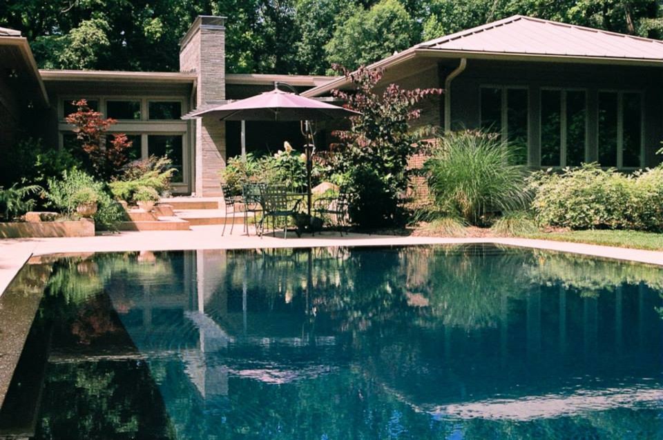 Photo of a large retro back rectangular infinity swimming pool in Charlotte with concrete slabs.