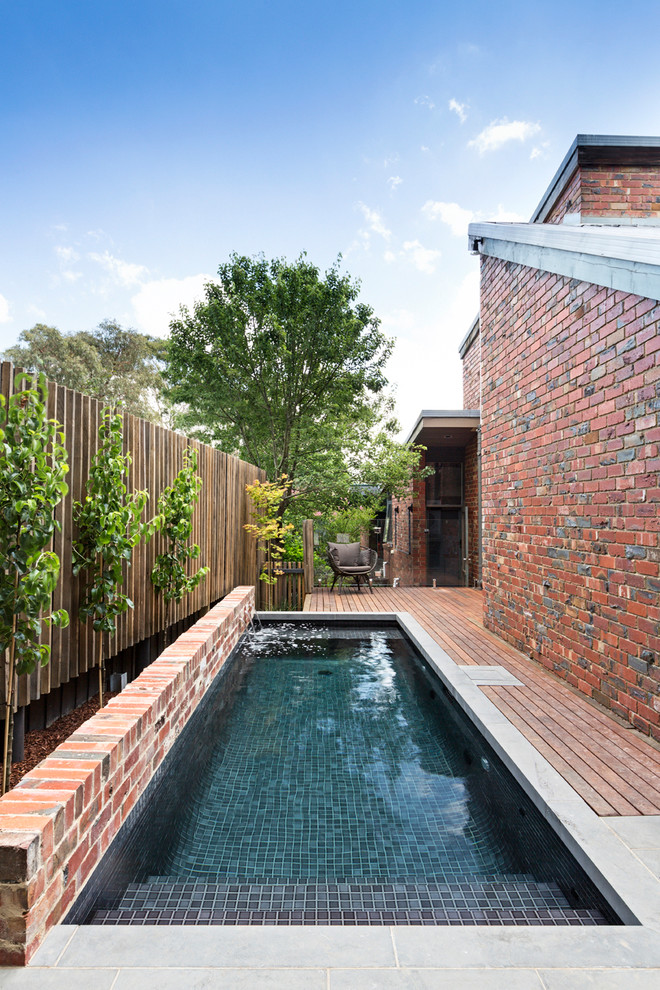 Réalisation d'une petite piscine design rectangle avec un point d'eau et une terrasse en bois.