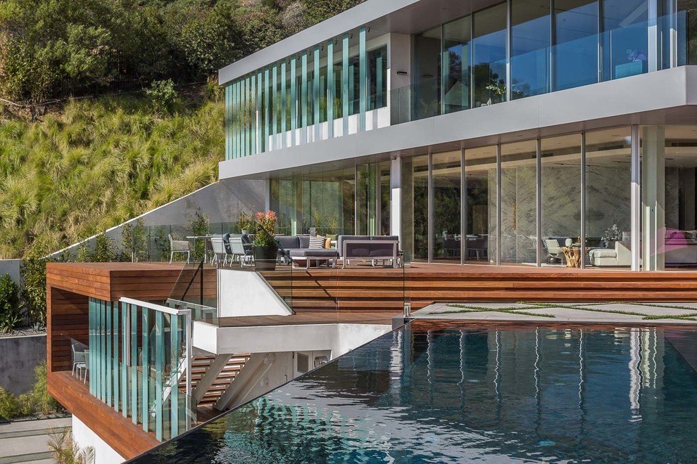 Immagine di un'ampia piscina a sfioro infinito minimalista personalizzata dietro casa con pedane