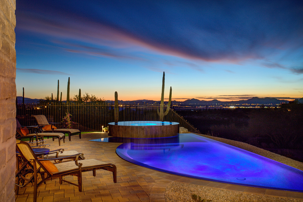 Diseño de piscinas y jacuzzis infinitos de estilo americano grandes a medida en patio trasero con adoquines de piedra natural