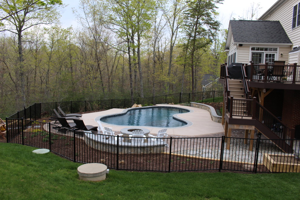Esempio di una piscina naturale classica personalizzata di medie dimensioni e dietro casa con fontane e pavimentazioni in cemento