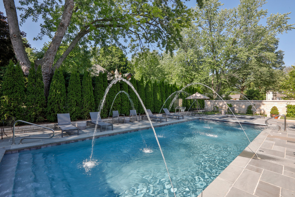 Foto de piscinas y jacuzzis alargados tradicionales de tamaño medio rectangulares en patio trasero con adoquines de piedra natural