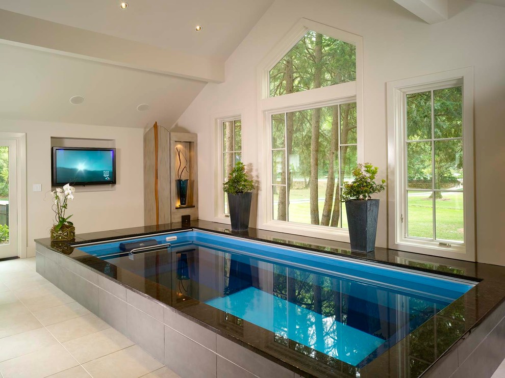 На фото: наземный, прямоугольный бассейн среднего размера в доме в стиле модернизм с покрытием из плитки с
