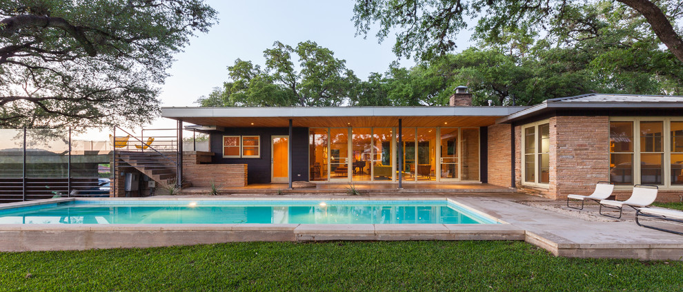 Example of a mid-century modern backyard rectangular and concrete paver pool design in Austin
