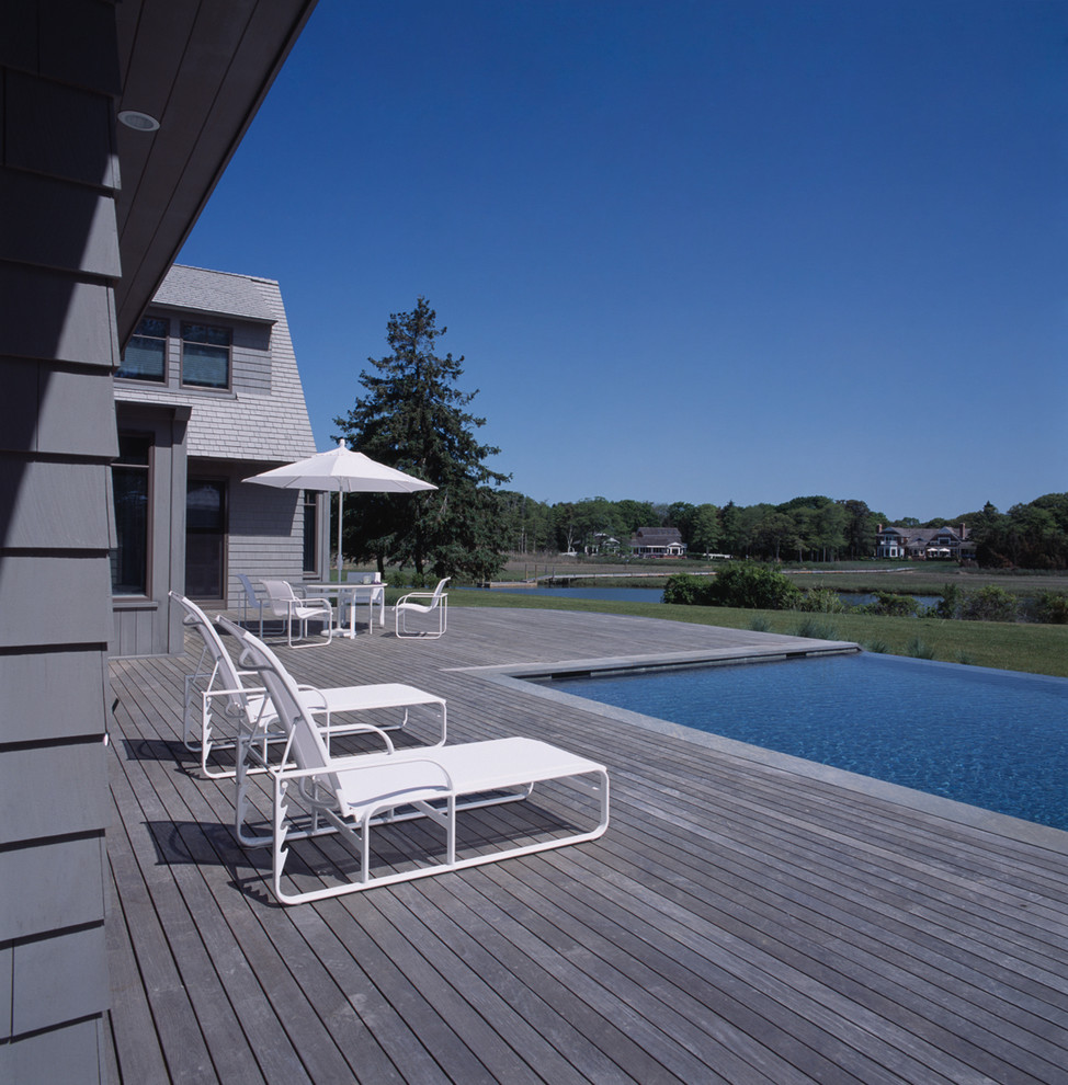 Cette image montre une piscine à débordement et arrière marine de taille moyenne et rectangle avec une terrasse en bois.
