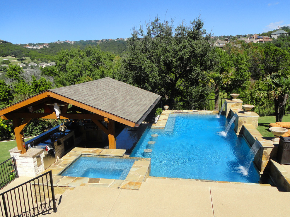 Großer Moderner Pool hinter dem Haus in rechteckiger Form mit Wasserspiel und Natursteinplatten in Austin