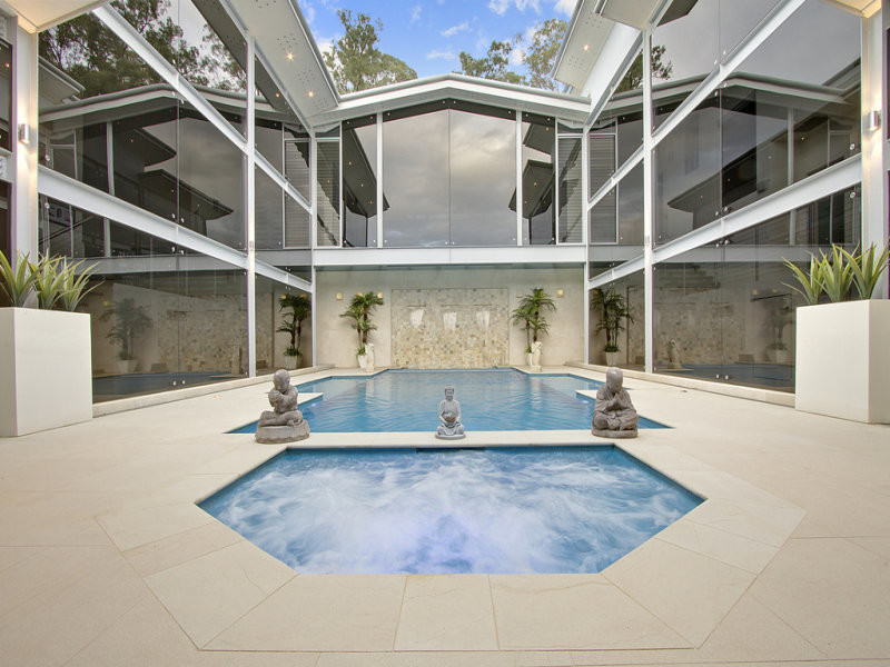 На фото: большой прямоугольный бассейн на внутреннем дворе в стиле модернизм с фонтаном и покрытием из каменной брусчатки с