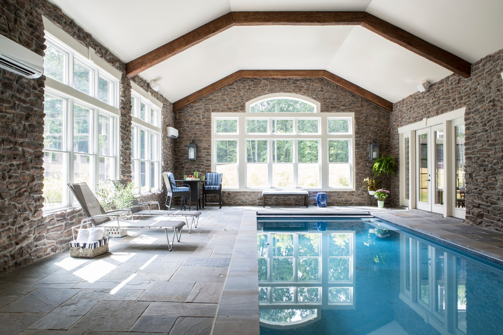 Esempio di un'ampia piscina coperta monocorsia tradizionale rettangolare con pavimentazioni in pietra naturale