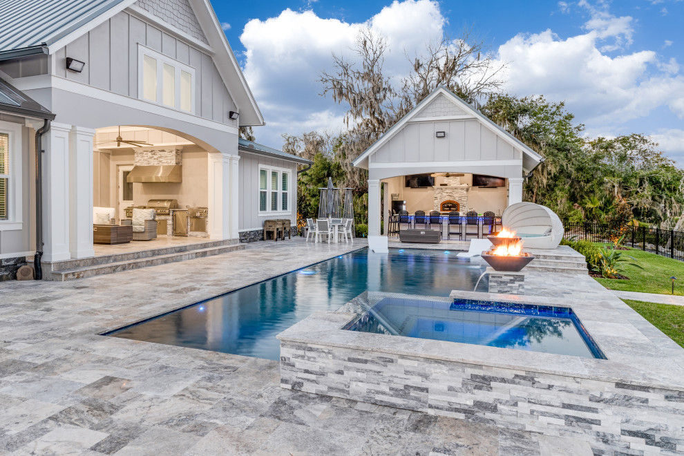 Пример оригинального дизайна: большой естественный, прямоугольный бассейн на заднем дворе в морском стиле с домиком у бассейна и покрытием из каменной брусчатки