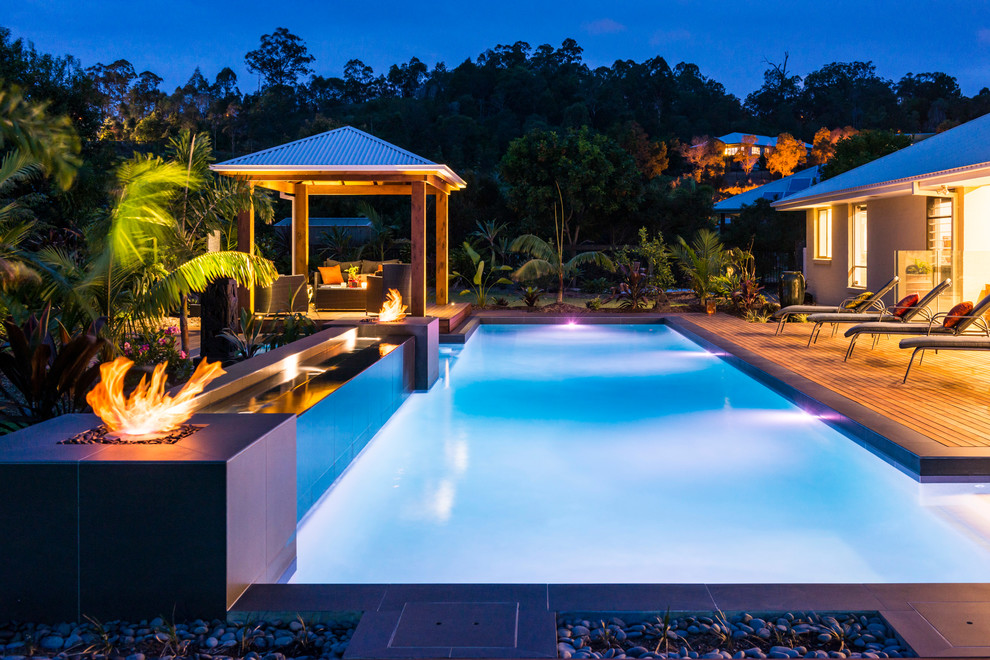 Idées déco pour une grande piscine exotique rectangle avec une terrasse en bois.