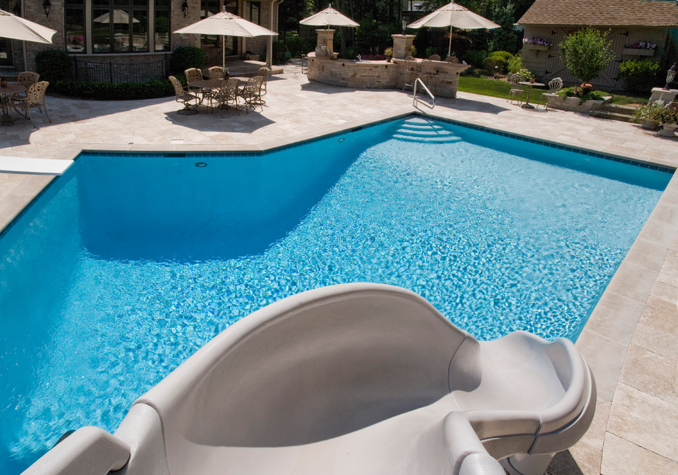 Modelo de piscinas y jacuzzis alargados actuales de tamaño medio a medida en patio trasero con adoquines de piedra natural