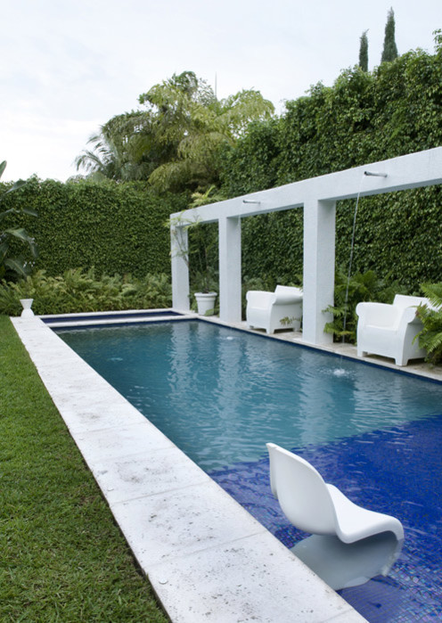 Großes Modernes Sportbecken hinter dem Haus in rechteckiger Form mit Wasserspiel und Natursteinplatten in Miami