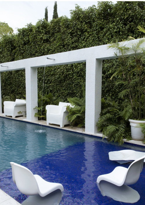 Großes Modernes Sportbecken hinter dem Haus in rechteckiger Form mit Wasserspiel und Natursteinplatten in Miami
