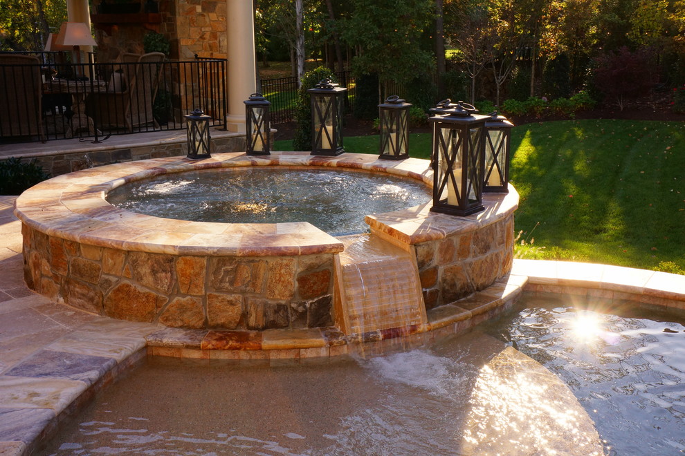 Exemple d'une piscine arrière tendance de taille moyenne avec un bain bouillonnant et des pavés en pierre naturelle.