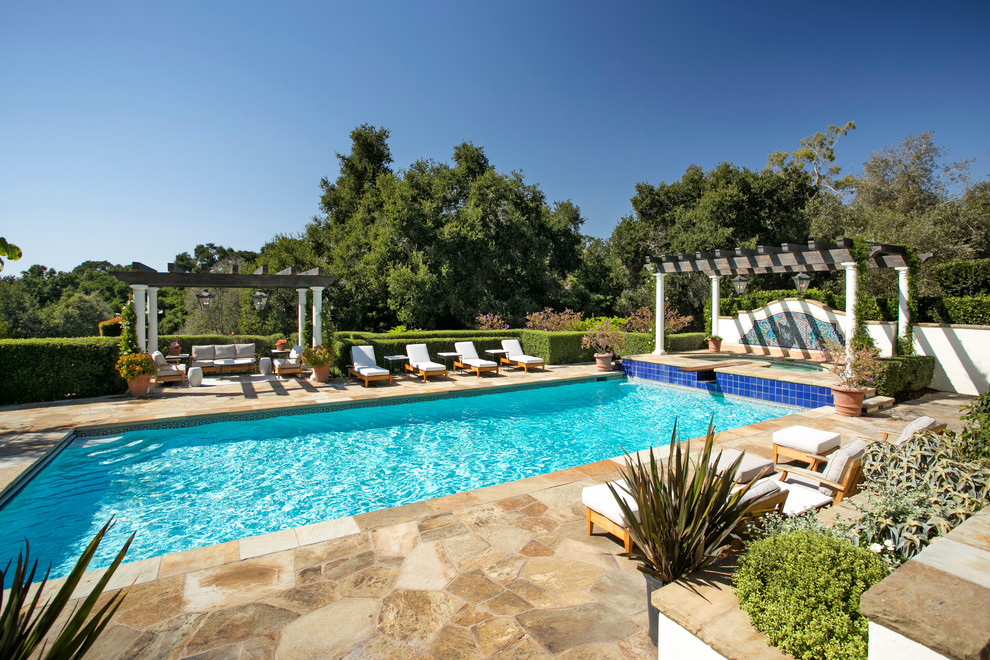Modelo de piscina mediterránea rectangular en patio trasero con adoquines de piedra natural