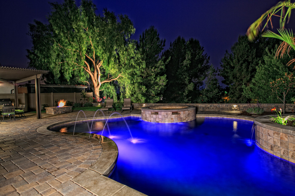 Ejemplo de piscinas y jacuzzis naturales clásicos grandes a medida en patio trasero con adoquines de hormigón