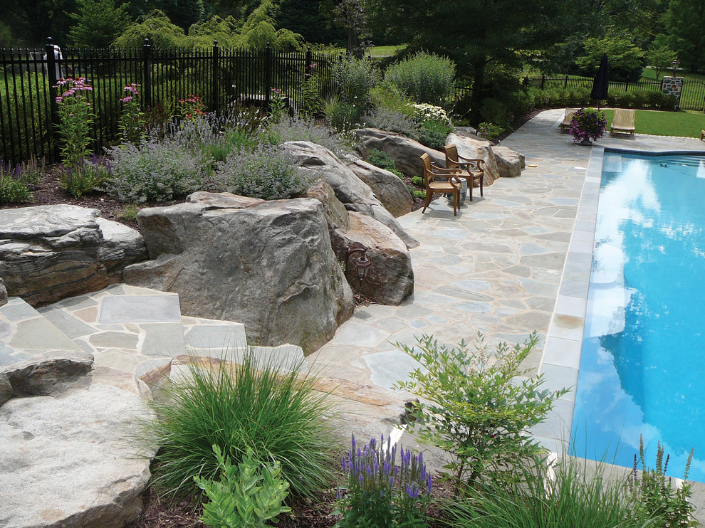 Foto di una piscina design rettangolare dietro casa con pavimentazioni in pietra naturale
