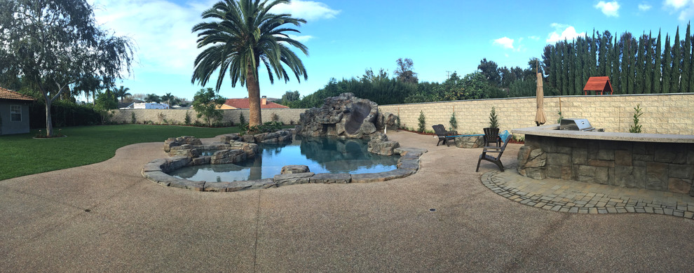 Imagen de piscina con tobogán natural tropical grande a medida en patio trasero