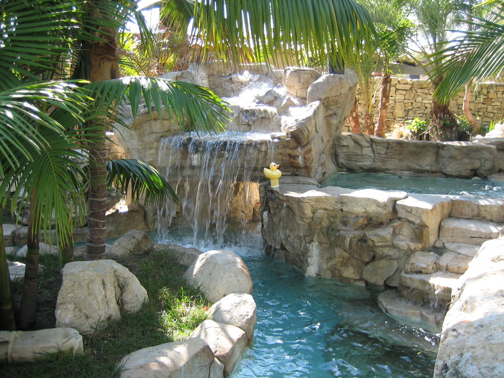 Esempio di una grande piscina tropicale personalizzata dietro casa con fontane