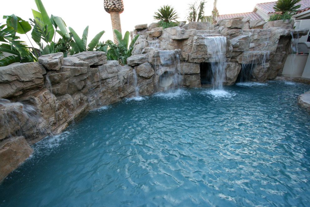 Idée de décoration pour une grande piscine naturelle et arrière sur mesure avec un point d'eau.