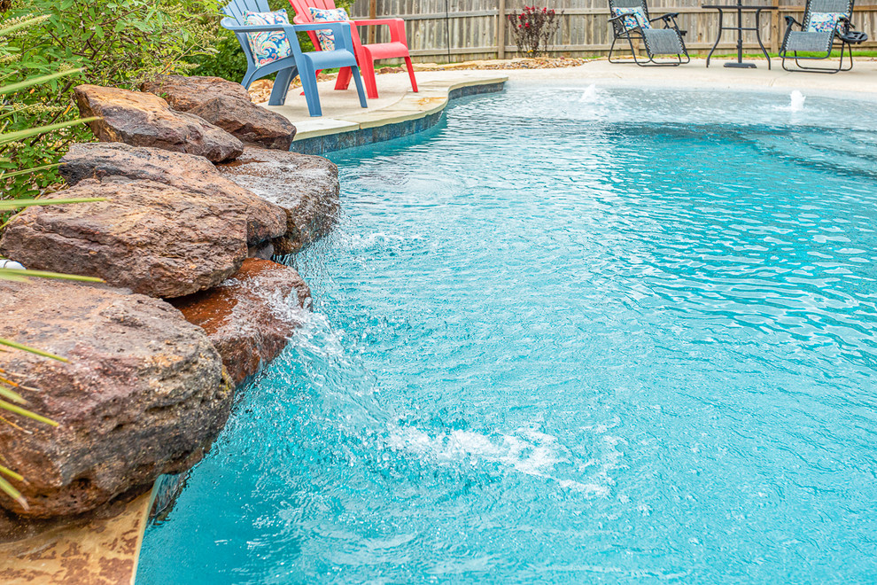 Cette image montre une piscine naturelle et arrière marine en forme de haricot de taille moyenne avec une dalle de béton.