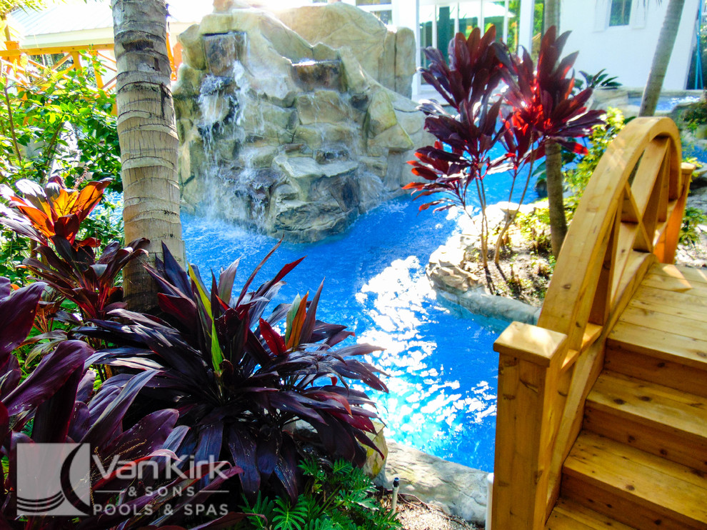 Imagen de piscina con fuente natural exótica extra grande a medida en patio trasero con adoquines de piedra natural