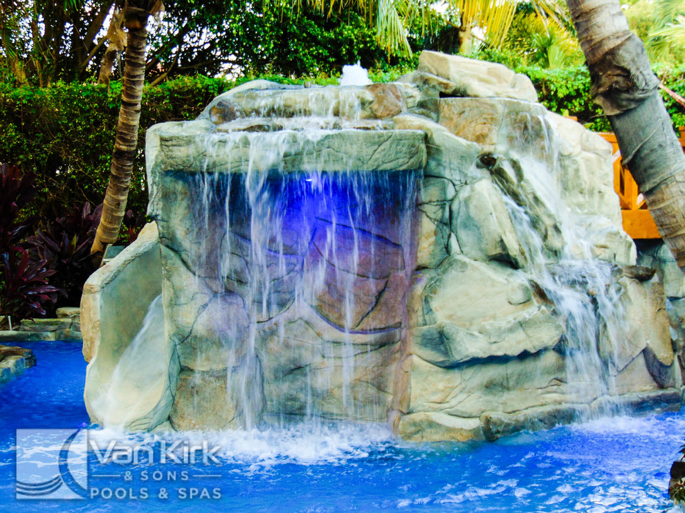 На фото: огромный естественный бассейн произвольной формы на заднем дворе в морском стиле с фонтаном и покрытием из каменной брусчатки