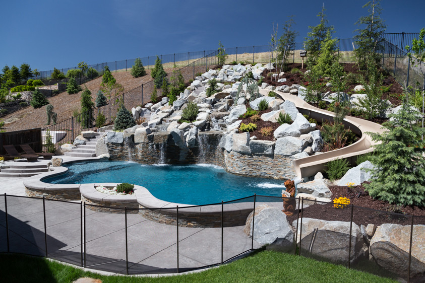 Ispirazione per una grande piscina tropicale personalizzata dietro casa con un acquascivolo e cemento stampato