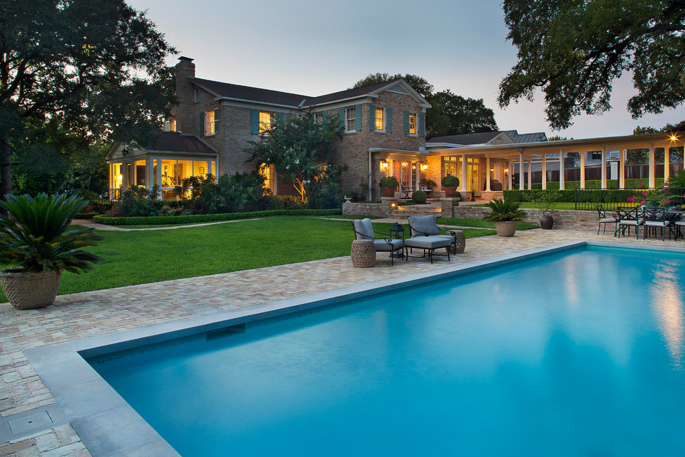 Classic back rectangular swimming pool in Austin with brick paving.